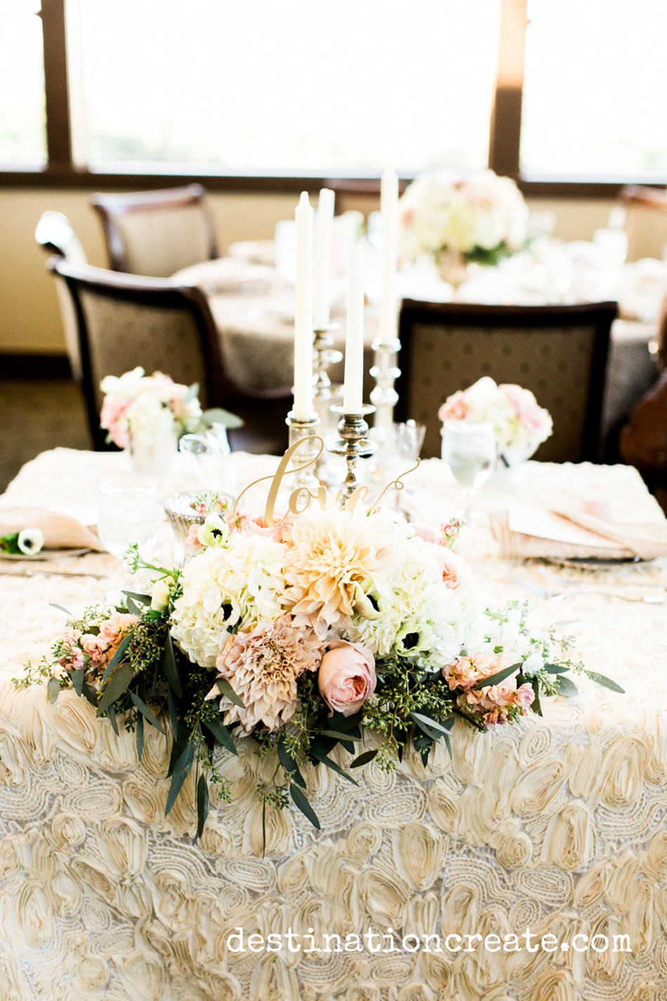 Lush, romantic centerpieces rise above champagne crinkle linens and fill the room with elegance at this gold and blush wedding in Golden Colorado held at Rolling Hills Country Club
