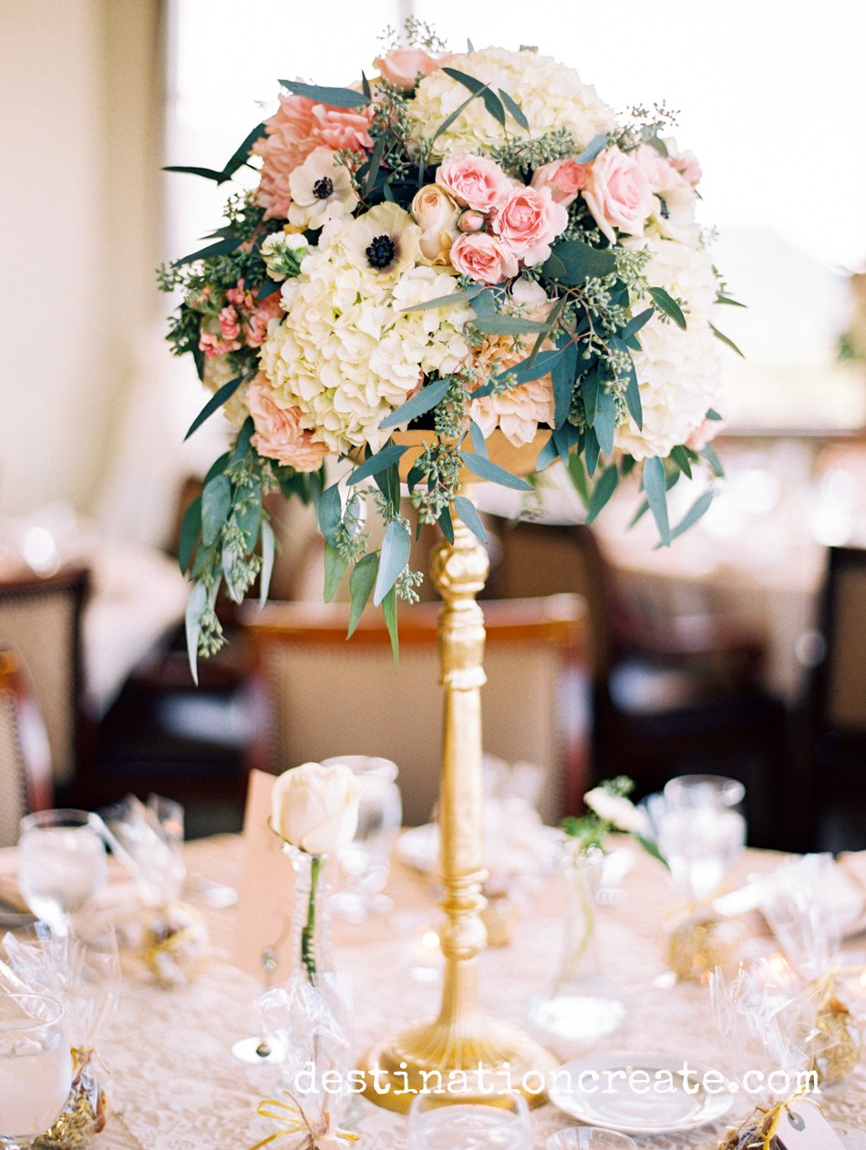 Lush, romantic centerpieces rise above champagne crinkle linens and fill the room with elegance at this gold and blush wedding in Golden Colorado held at Rolling Hills Country Club